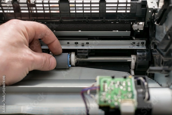 Fototapeta closeup, the hand of the service center master changes the rubber grip roller in the disassembled printer