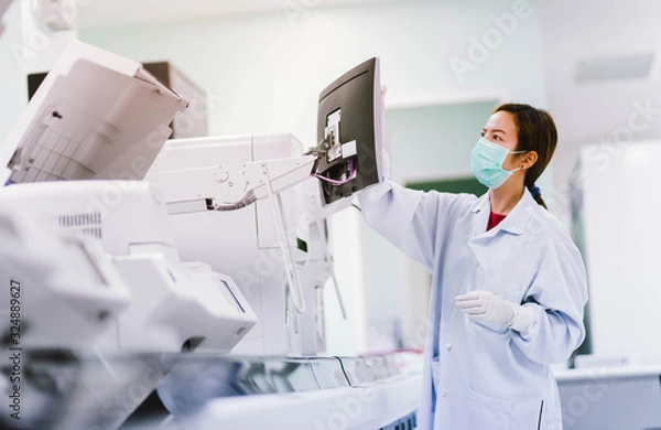 Fototapeta young female laboratory technician working with automation blood  analyzer in medical laboratory