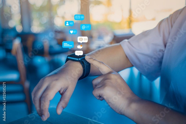 Fototapeta Person using a social media marketing concept on smartwatch with notification icons of like, message, comment and star above smartwatch screen.