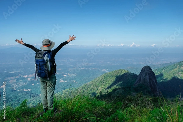 Obraz rear view of women stading on cliff and push hands up against mountain and tree
