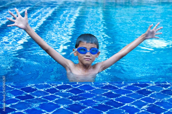 Obraz Portrait of asian boy having fun and show up hands in swimming pool and blue refreshing water