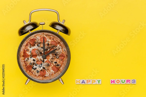 Fototapeta Alarm clock with pizza dial on yellow background with words "Happy Hours" of cube letters