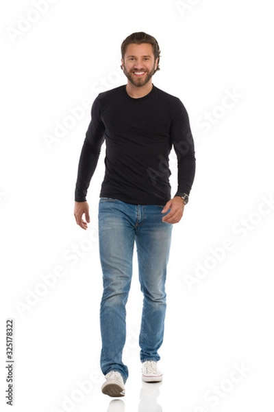 Fototapeta Handsome Man In Black Blouse, Jeans And Sneakers Is Walking Towards Camera And Smiling