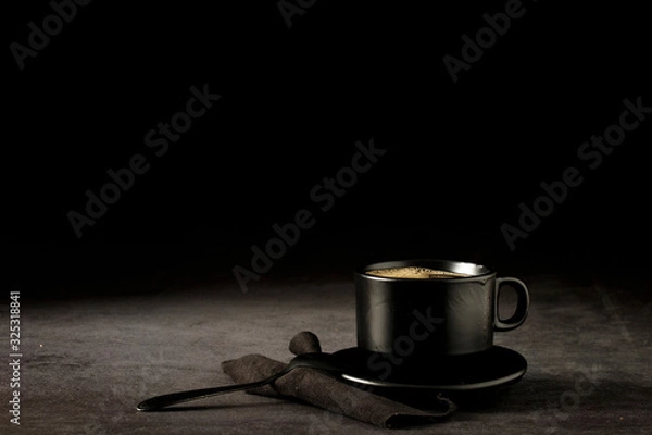 Fototapeta Black coffee cup with coffee on a dark background. With copy space for your text. Cup of coffee on a black background low key copy space.