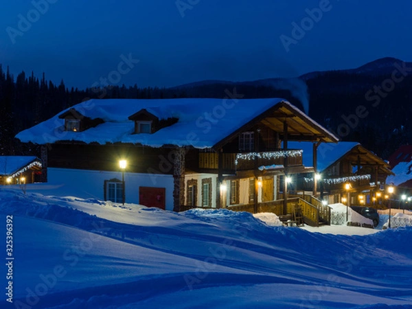 Fototapeta Ski resort Gornaya Salanga at night. Blue twilight is falling, a yellow cozy warm light has lit up in the houses. Winter in Siberia