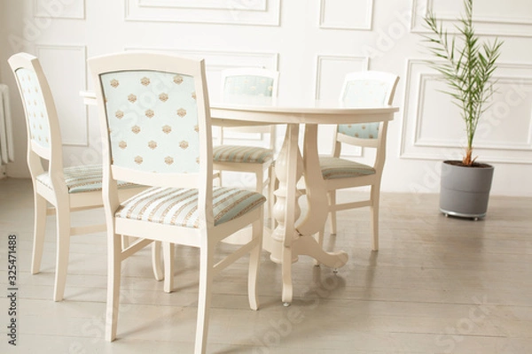 Fototapeta White tables and chairs for dinner in a classic interior. Upholstered chairs for comfortable sitting at the table
