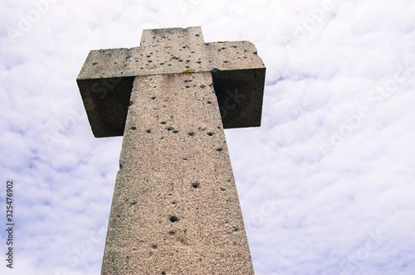 Obraz Stone cross with sky background and bullet holes marks from world war 2