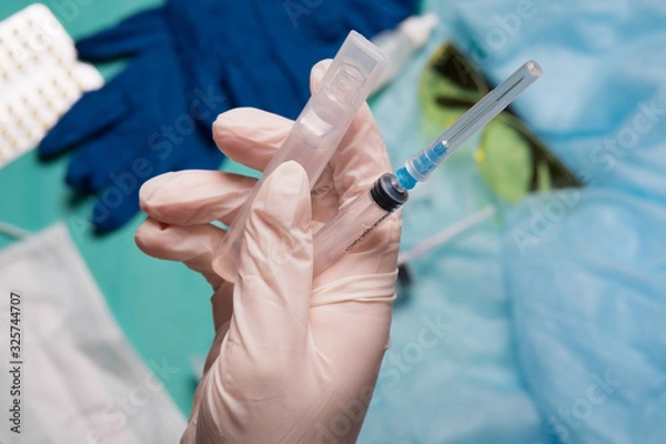 Fototapeta Doctor's hand holds a syringe. Hand with a syringe on a background of medical instruments.