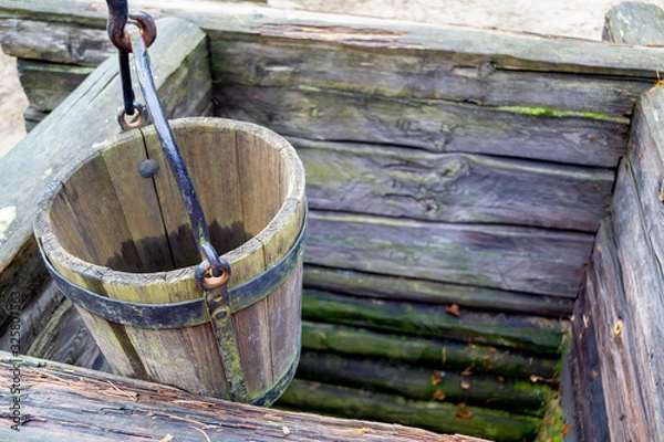 Obraz Old wooden well and a wooden bucket. The concept of rural areas and recreation in the village.