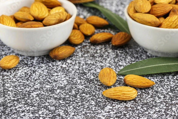 Obraz Two white bowls with almonds stand on a black and white marble surface