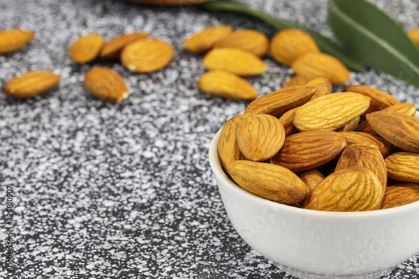 Obraz White bowl with almonds on a black and white marble surface