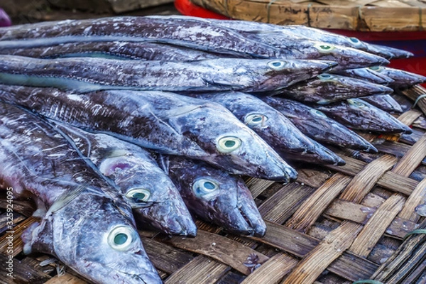 Obraz Seafood market. Side and close up view of freshly caught fish on the counter for sale. The fish are laid out on a wicker counter.