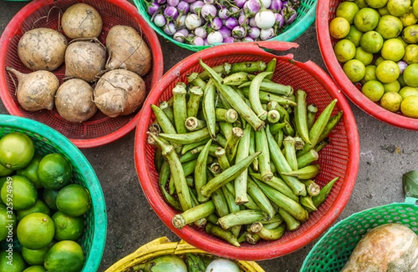 Obraz Typical Asian street market for fruits and vegetables. Close up and top view of vegetables for sale in round plastic containers.  