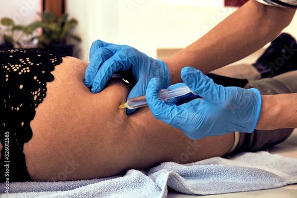 Fototapeta Woman lying on bed and getting Botox injection.