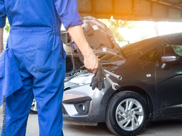 Fototapeta Auto mechanic working in garage. Repair service.Hand of car mechanic with wrench.