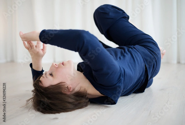 Fototapeta Woman lies on the floor and practices bodily practice in the gym.