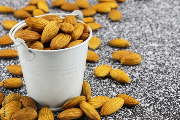 Obraz Almonds in a white bucket and on black and white marble