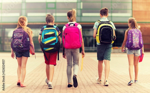 Fototapeta primary education, friendship, childhood and people concept - group of happy elementary school students with backpacks walking outdoors from back