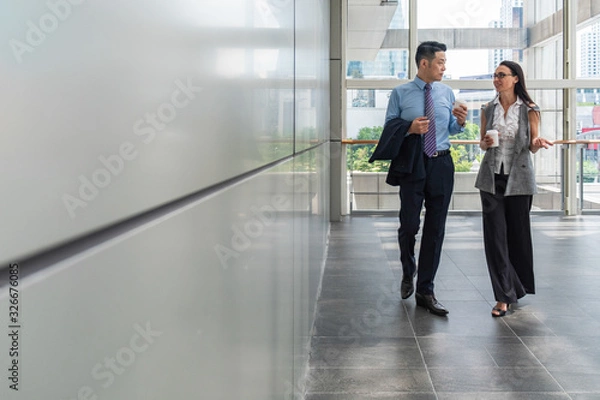 Obraz Business people walking in hallway with big windows stock photo