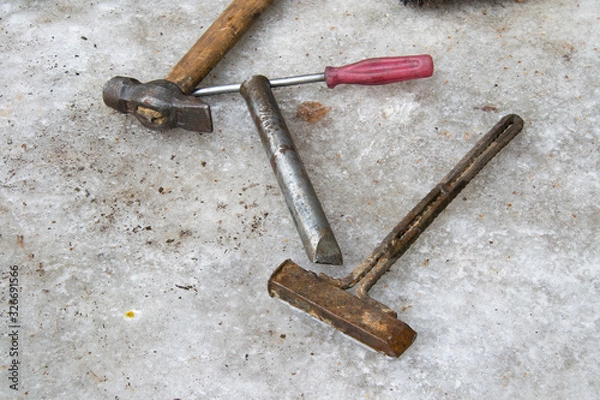 Fototapeta Old dirty tool: hammer, screwdriver, chisel, homemade rusty hammer wallow on ice in winter. A very scary repairman tool in Russia.
