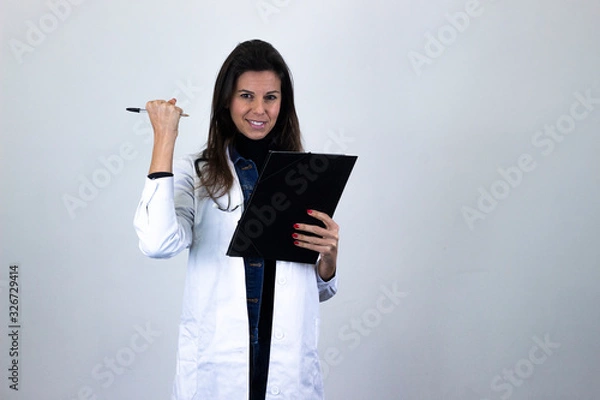 Fototapeta Portrait of attractive caucasian middle age woman with a folder in her hands showing thumb up gesture. Nurse, doctor, scientist, therapist, pharmacist, isolated on gray background studio shot, in whit