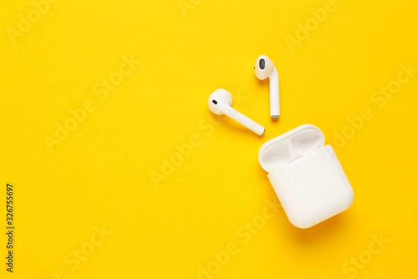 Obraz White wireless earphones on yellow background
