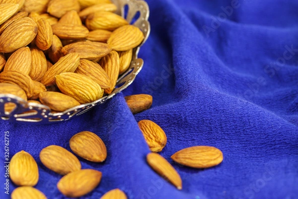 Obraz Almonds in a metal vase on a blue background