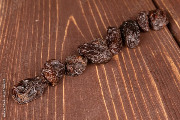 Fototapeta Lot of whole dried dark raisin diagonal on brown wood