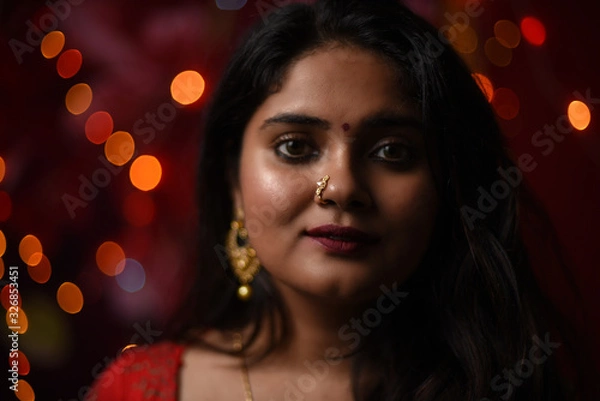 Fototapeta Close up portrait of an Indian Bengali beautiful brunette woman in front of the colorful light bokeh background created by tiny chain lights  in the evening of Diwali. Indian lifestyle and religion.
