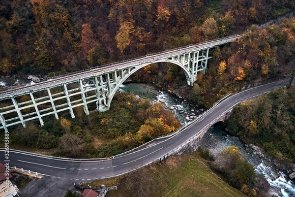 Fototapeta high autumn alpine speed road in Italian Alps and railway bridge over the mountain river.