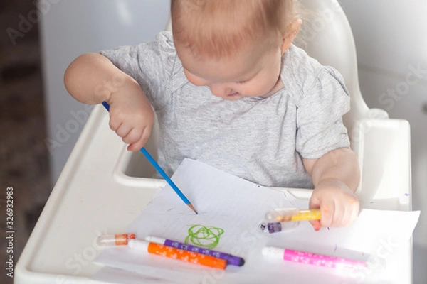 Fototapeta Cute baby paint using colorful pencils on white table