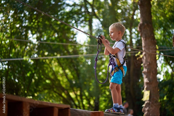 Obraz Little boy overcomes the obstacle in the rope park.