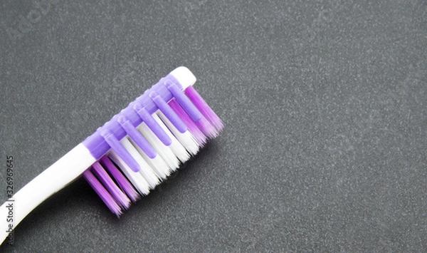 Fototapeta Close-up of the head of a pink and white toothbrush on a black textured background. Good quality