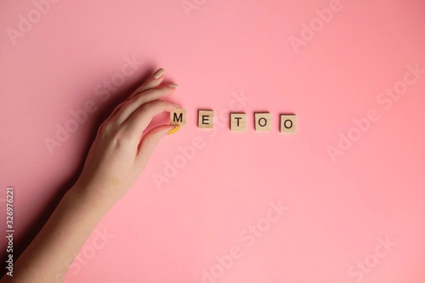 Fototapeta Woman hand making MeToo word with wooden alphabet on pink background, used for concept of sexual harrassment.
