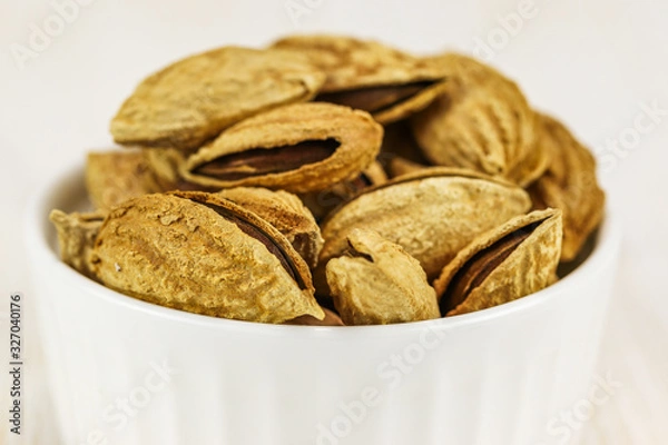 Obraz Inshell almonds in a white bowl on a white background