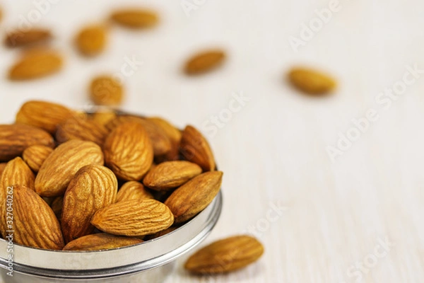 Obraz Almonds in a metal bowl and on a white surface