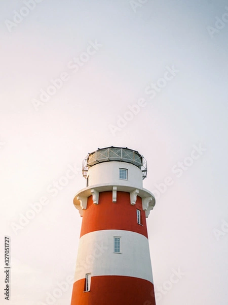 Obraz View of white and red lighthouse on clear sky at the sunset