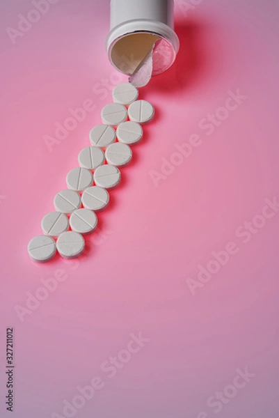 Fototapeta White round tablets scattered near plastic bottle of pills on pink background