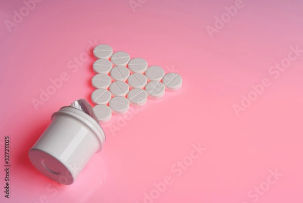 Fototapeta White round tablets scattered near plastic bottle of pills