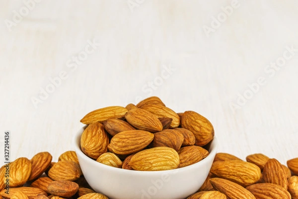Obraz Almonds in a white bowl and on a white background