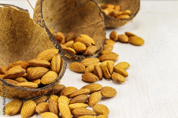 Obraz Almonds in half a coconut shell and on a white background