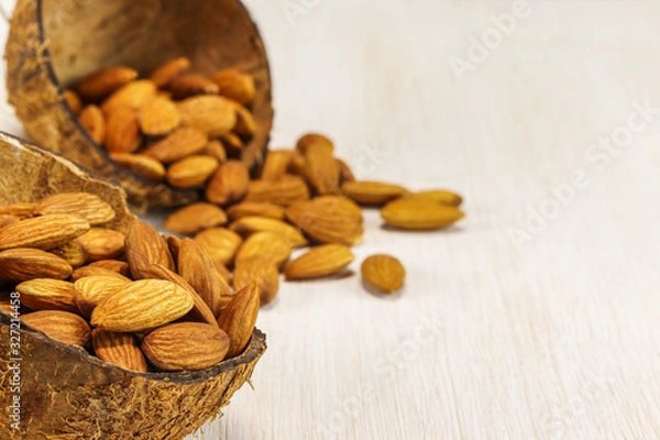 Obraz Two half coconut shell with almonds on a white background