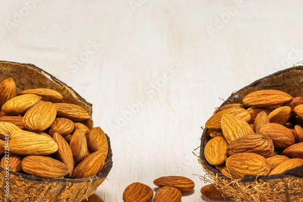 Obraz Almond nuts in two half coconut on a white background