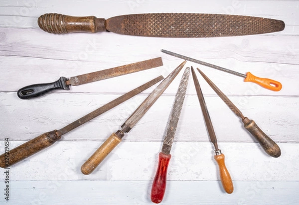 Fototapeta Sets of different wood rasps of different sizes in the middle of an old wooden floor background. top view