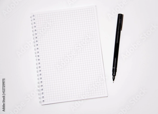 Obraz Squared notebook with black pen on a white background. Record ideas, notes, plans, tasks.  Notebook top and side view. Flatlay. Copy Space