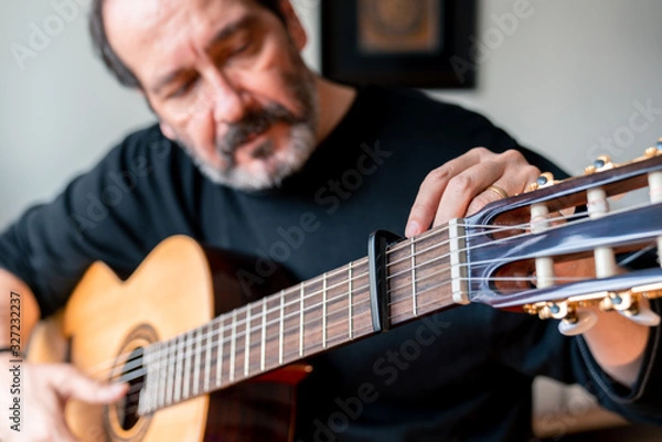 Obraz Seniors man are playing a guitar at home. Retired man learning playing a guitar.