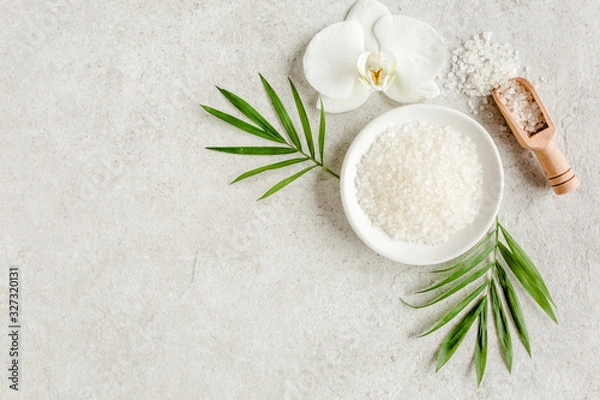 Fototapeta Koncepcja leczenia uzdrowiskowego. Naturalne / organiczne kosmetyki spa, sól morska i liście palm tropikalnych na stole z szarego marmuru od góry. Tło Spa z miejscem na tekst, płaskie lay, widok z góry.