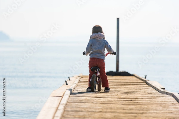 Fototapeta Enfant seul en vélo sur un ponton