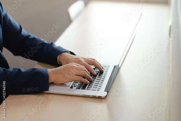 Fototapeta close up hands of a businessman typing text on laptop in office, business concept