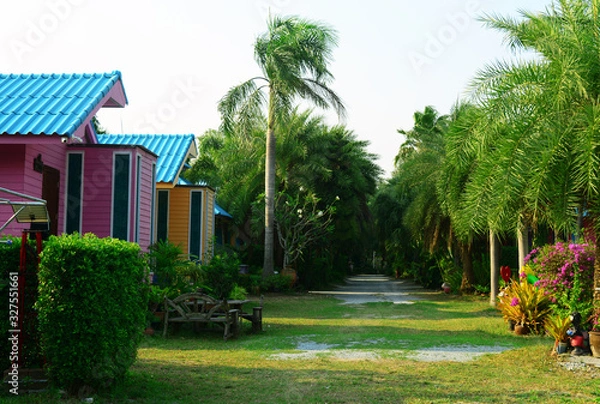 Obraz the house in garden resort with the palm trees,flowers ,green ornamental plant and lawn with blank sky